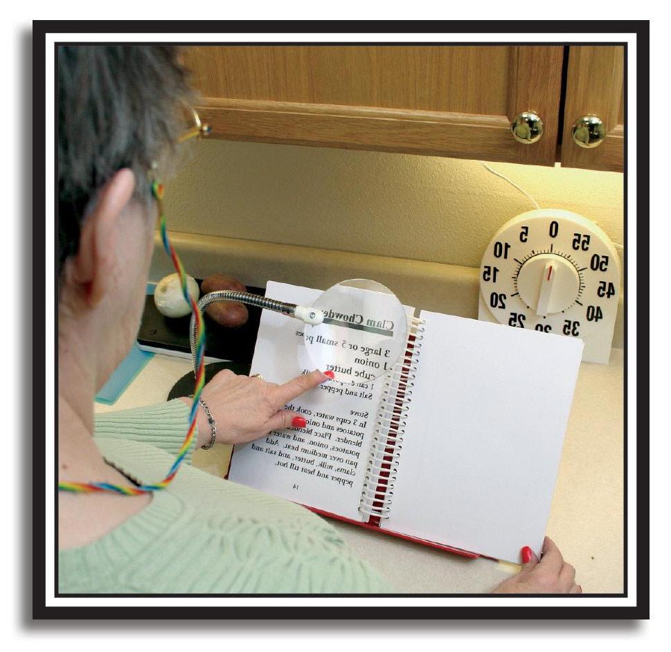一个女人在厨房用放大镜看食谱的照片